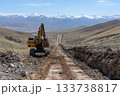 Excavator building a long dirt road through a wide mountain valley with rocky terrain 133738817