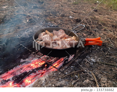 close up meat and pieces of lard are fried in a tourist pan on coals with smoke close up meat and pieces of lard are fried in a tourist pan on coals with smoke 133738882