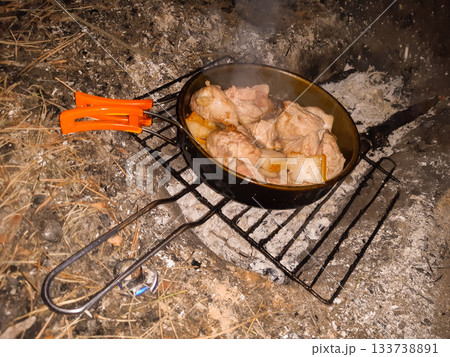 top view of fried meat with pieces of lard in a pan on a grate in the forest top view of fried meat with pieces of lard in a pan on a grate in the forest 133738891