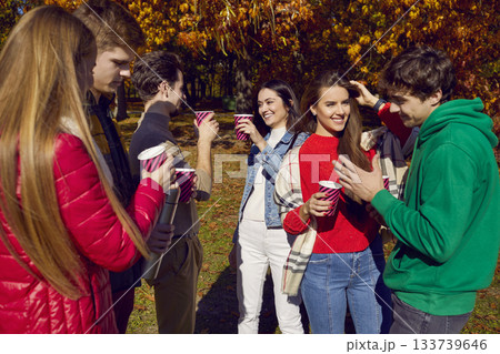 Happy friends having fun standing together with drinks in park 133739646