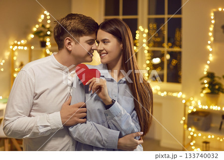 Happy Couple Embraces with Red Heart at Home 133740032