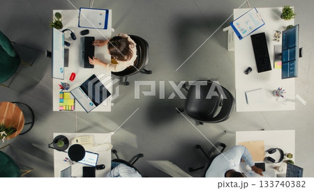 Top down view of work team engaged in negotiation consulting during business meeting. Employees use laptops to analyze finance data and performance reports in office. 133740382