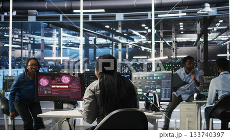 Server hub coworkers react to security breach after unauthorized access bypassing firewall compromising data. Employees initiate emergency response protocols after cybersecurity alert, camera A 133740397