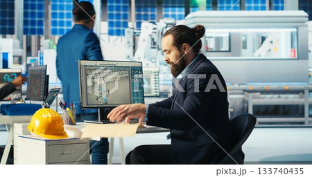 Solar panel manufacturing plant researcher taking notes while developing new solar energy systems prototypes. Specialist researching new photovoltaics materials in factory office, writing down info 133740435