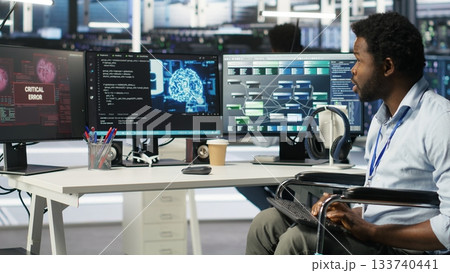 Stressed engineer with paraplegia in data center panicked by AI node tree software critical error. Anxious server hub worker in wheelchair worried by visual programming tool glitching, camera B 133740441
