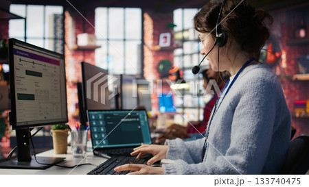 Call center employee starting job shift, sitting down at desk, handling complaints. Customer service agent arriving at work, listening to customer needs related to products or services, camera B Call center employee starting job shift, sitting down at desk, handling complaints. Customer service agent arriving at work, listening to customer needs related to products or services, camera B 133740475