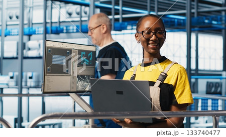 Portrait of happy engineer in smart photovoltaics factory looking at system performance metrics. Cheerful worker in solar panels plant tracking energy production through IoT sensors, camera A 133740477