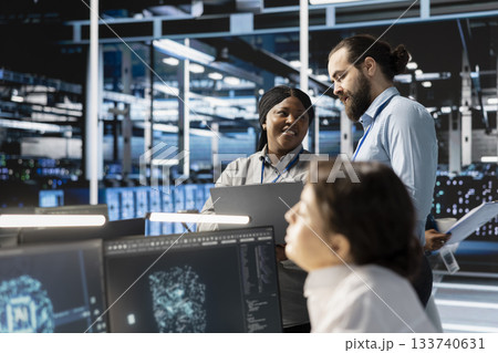 Team of engineers in data center integrating AI driven automation tools, doing maintenance. Teamworking colleagues in server room using artificial intelligence machine learning models 133740631