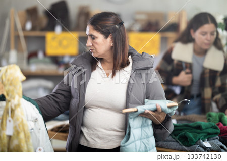 Latina Female shopper selects vest in fashionable clothing boutique Latina Female shopper selects vest in fashionable clothing boutique 133742130