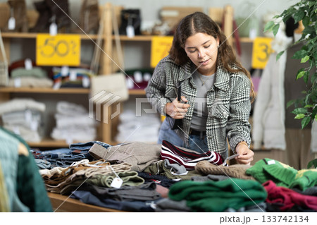 Young woman chooses sweater in clothing store 133742134