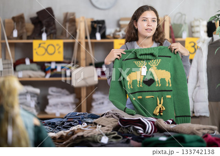 Young woman chooses sweater in clothing store Young woman chooses sweater in clothing store 133742138