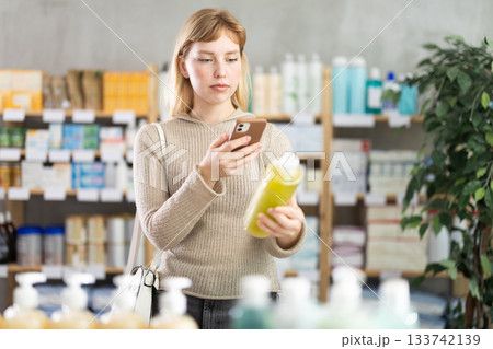 Young woman scanning qr code of shampoo Young woman scanning qr code of shampoo 133742139