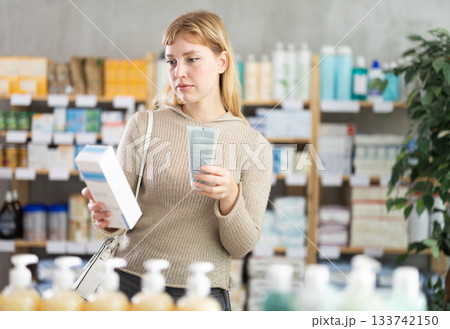 Girl in autumn clothes choosing skin cream at drugstore Girl in autumn clothes choosing skin cream at drugstore 133742150