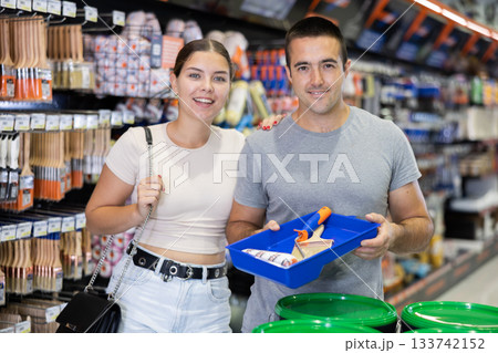 Couple bought brushes and tray pallet expendable materials in paint department of construction store 133742152