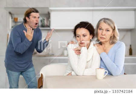 Old woman comforts her daughter while her husband yells at her Old woman comforts her daughter while her husband yells at her 133742184