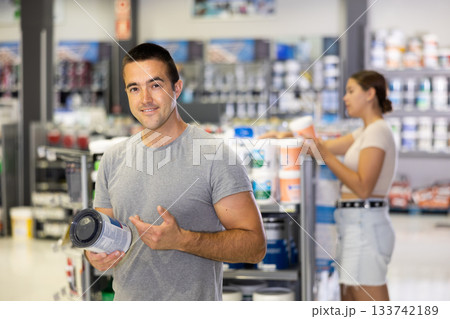 Smiling man standing in hardware store with can of paint Smiling man standing in hardware store with can of paint 133742189