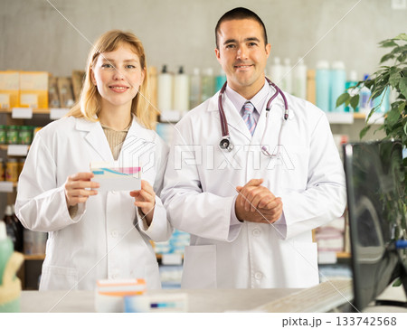Young pharmacists inviting clients in chemist's shop Young pharmacists inviting clients in chemist's shop 133742568
