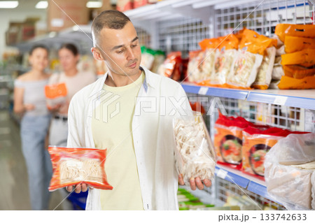 Pensive shopper choosing Asian noodles at grocery store 133742633