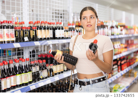 Young woman choosing soy sauce in store 133742655