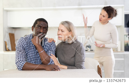 Old woman trying to calm angry man while middle-aged woman quarreling to him 133742673