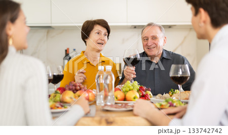Senior man and woman sitting with their grown children during family holiday table in kitchen Senior man and woman sitting with their grown children during family holiday table in kitchen 133742742