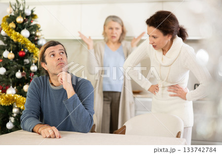 Elderly mother and woman during family quarrel accuse adult man on Christmas Eve Elderly mother and woman during family quarrel accuse adult man on Christmas Eve 133742784