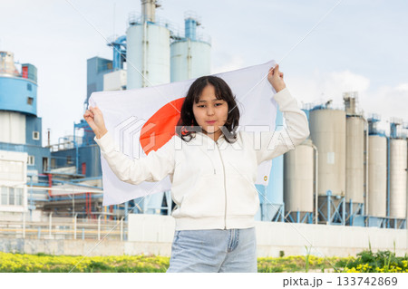 National flag of Japan in hands of girl against background of modern factory 133742869