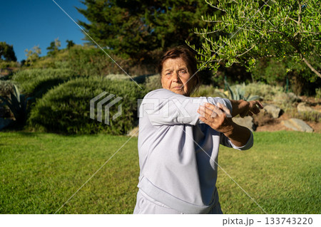 Determined senior woman in sportswear stretching Determined senior woman in sportswear stretching 133743220