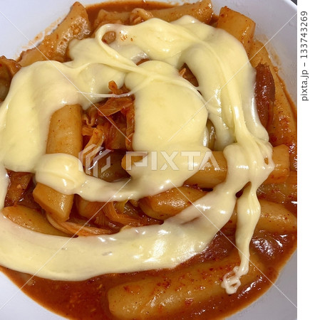 Spicy Korean tteokbokki with chewy rice cakes in a vibrant red sauce, topped with sesame seeds and green onions. A popular street food known for its addictive flavor and satisfying texture. 133743269