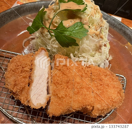 Crispy tonkatsu, a Japanese-style breaded and deep-fried pork cutlet, served with shredded cabbage and drizzled with savory sauce. A delightful balance of crunchy texture and juicy meat. Crispy tonkatsu, a Japanese-style breaded and deep-fried pork cutlet, served with shredded cabbage and drizzled with savory sauce. A delightful balance of crunchy texture and juicy meat. 133743287