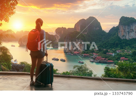 Young Woman with Backpack Gazing at Scenic Sunset Over Ocean 133743790