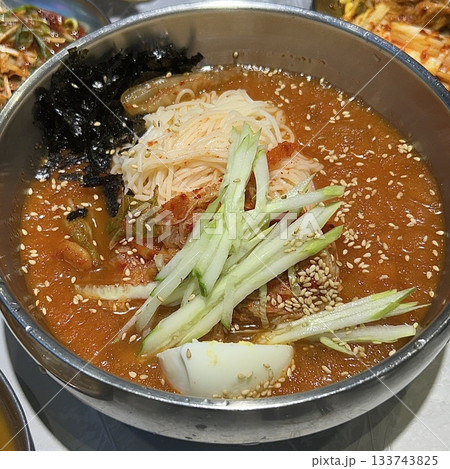 Chilled, chewy naengmyeon noodles in tangy broth paired with juicy, savory mandu dumplings, offering a perfect balance of refreshing coolness and hearty comfort in every delicious Korean bite. Chilled, chewy naengmyeon noodles in tangy broth paired with juicy, savory mandu dumplings, offering a perfect balance of refreshing coolness and hearty comfort in every delicious Korean bite. 133743825