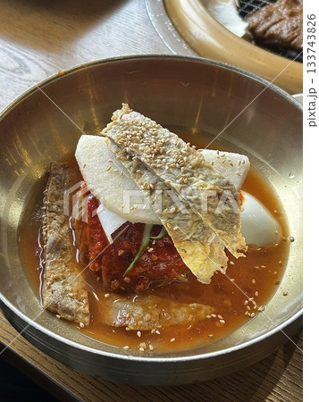 Chilled, chewy naengmyeon noodles in tangy broth paired with juicy, savory mandu dumplings, offering a perfect balance of refreshing coolness and hearty comfort in every delicious Korean bite. Chilled, chewy naengmyeon noodles in tangy broth paired with juicy, savory mandu dumplings, offering a perfect balance of refreshing coolness and hearty comfort in every delicious Korean bite. 133743826