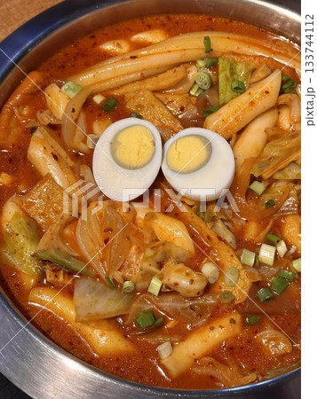 Spicy Korean tteokbokki with chewy rice cakes in a vibrant red sauce, topped with sesame seeds and green onions. A popular street food known for its addictive flavor and satisfying texture. Spicy Korean tteokbokki with chewy rice cakes in a vibrant red sauce, topped with sesame seeds and green onions. A popular street food known for its addictive flavor and satisfying texture. 133744112