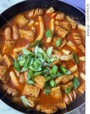 Spicy Korean tteokbokki with chewy rice cakes in a vibrant red sauce, topped with sesame seeds and green onions. A popular street food known for its addictive flavor and satisfying texture. 133744570