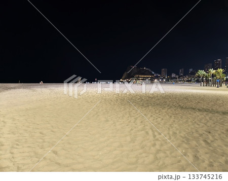 silent nighttime beach, peaceful shoreline under dark sky with distant city lights and vast quietude silent nighttime beach, peaceful shoreline under dark sky with distant city lights and vast quietude 133745216