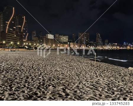 nighttime coastal landscape showcasing city lights and textured sand for travel and patrol themes 133745283