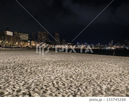 silent night shoreline, calm beach beneath cloudy sky, serene and quiet beach with cloudy night sky 133745288