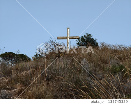 quiet hill adorned with cross and dry grasses, tranquil hillside featuring wooden cross and sparse quiet hill adorned with cross and dry grasses, tranquil hillside featuring wooden cross and sparse 133745329