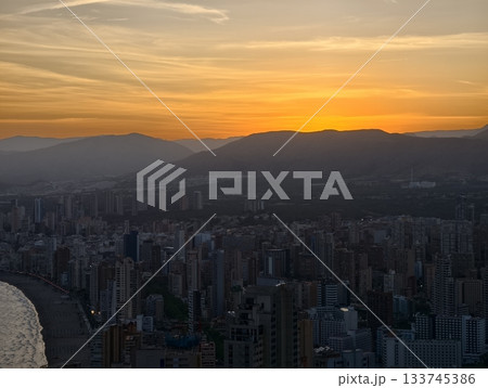 dramatic aerial scene, bay silhouette at sunset, sunset over coast with city and mountains 133745386