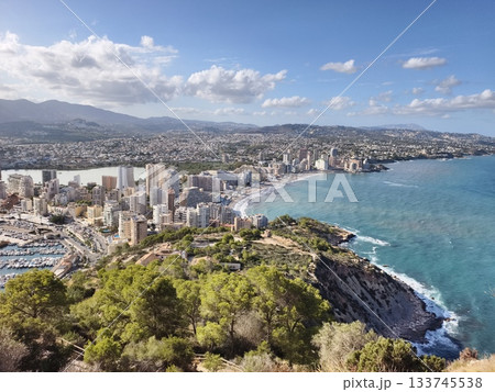 coastal aerial view, mountain backdrop behind serene coastal city with resorts and clear skies 133745538
