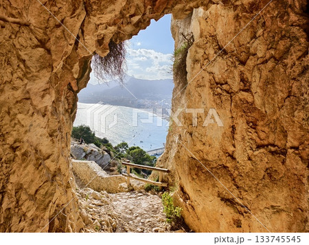emerald sea beyond tiny cave, narrow rocky entrance reveals glittering emerald waters and distant emerald sea beyond tiny cave, narrow rocky entrance reveals glittering emerald waters and distant 133745545