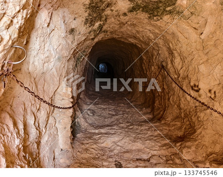 rugged tunnel suggests hidden journeys, narrow rocky corridor hints at adventures in darkness 133745546