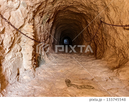 abandoned rusty mine shaft, weathered underground mine with rusted chains and uneven rocky terrain 133745548