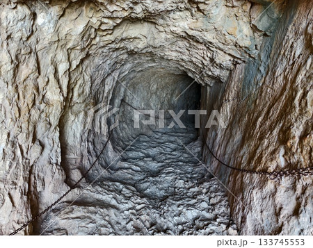 dark rocky underground passageway, enigmatic rugged mineral tunnel extending into dark depths 133745553