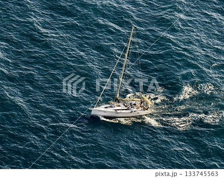 sailboat on ocean, sailboat drifting peacefully over vibrant turquoise sea with bright sun 133745563