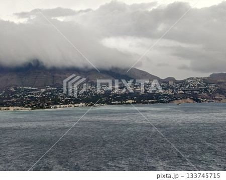 jagged coast with distant harbor, mountainous ridges lead to distant harbor under slatecolored sky 133745715