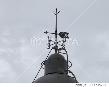 closeup of aged wind vane, closeup of aged weathered vane with rusty arrow under cloudy sky closeup of aged wind vane, closeup of aged weathered vane with rusty arrow under cloudy sky 133745724