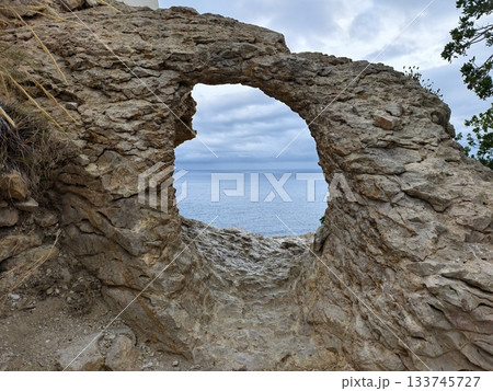 stone frame captures ocean scene, textured rock opening provides unique viewing for experts 133745727