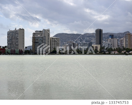 dense highrise cityscape beside peaceful green lake with mountain view and subtle reflections 133745753